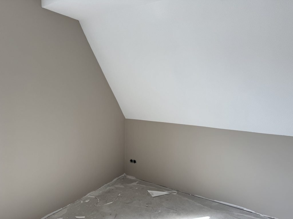 Zolderkamer in een nieuwbouwwoning met een schuine wand, afgewerkt in een warme grijstint